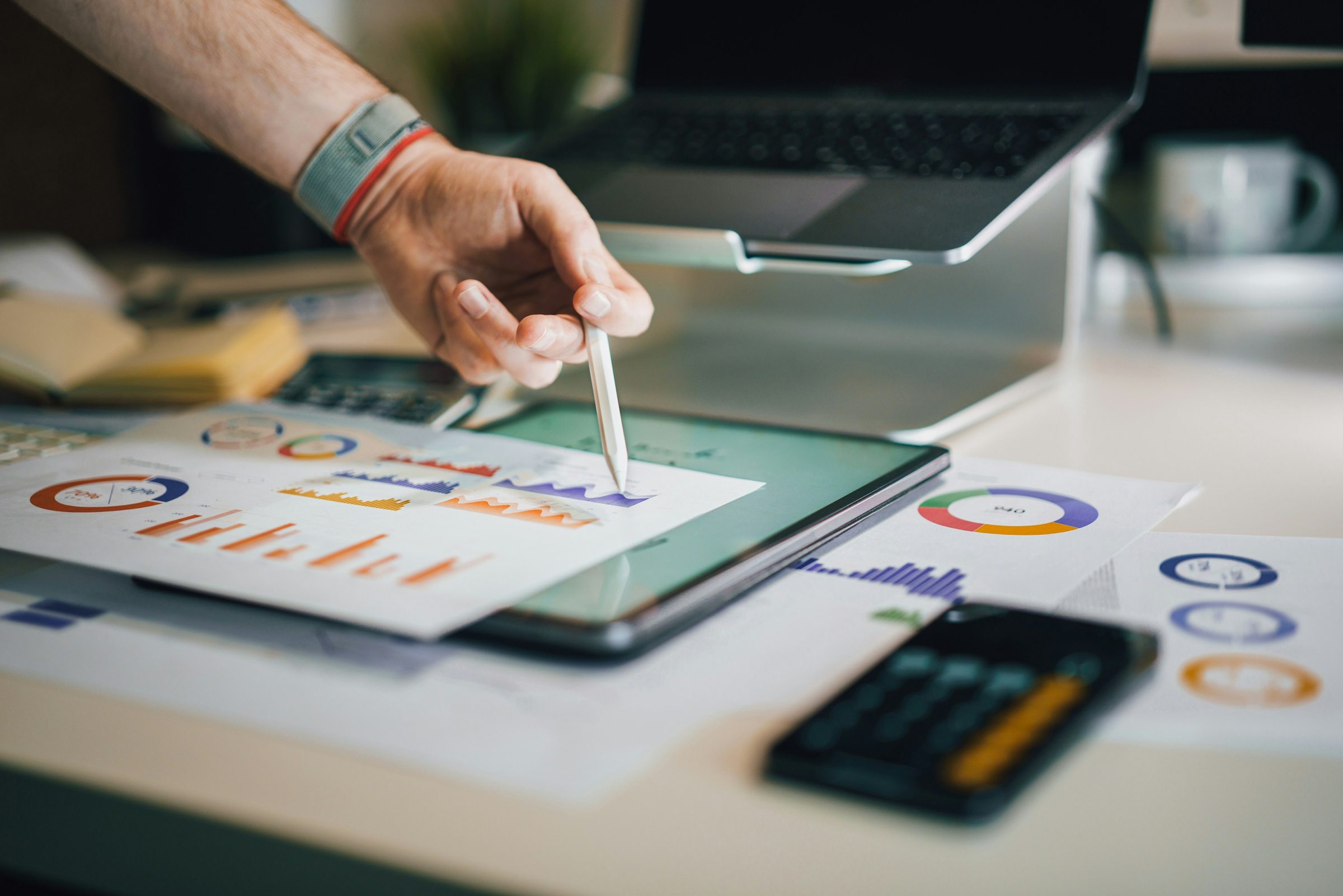 Hand with a stylus reviewing marketing charts on a tablet