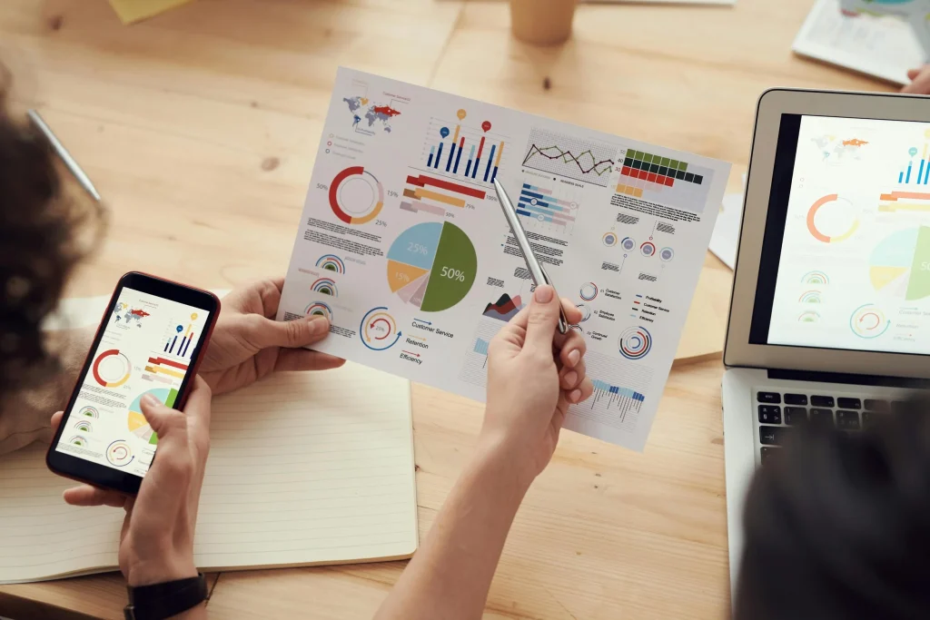 Hands reviewing printed charts and a phone dashboard at a desk